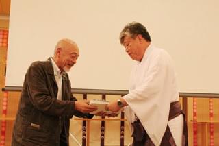 春日大社宮司の花山院弘匡氏に 作品を手渡す本橋成一監督「アレクセイと泉」